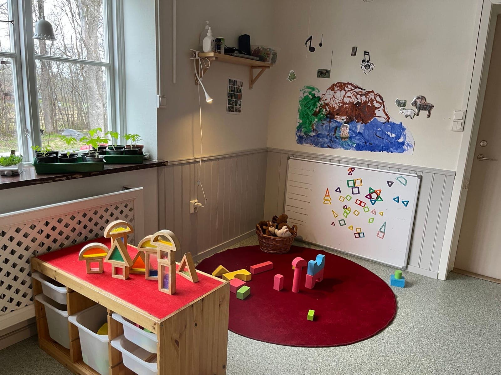 Samlingshörnan på Tussilago med byggklossar, matta och barnens målningar på väggen.